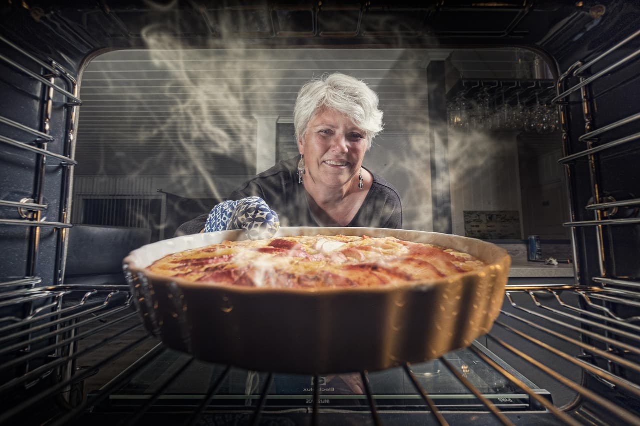 Femme âgée sortant une tarte du four